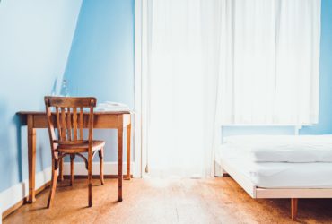 Zimmer mit Stuhl, Tisch, Bett und Fenster