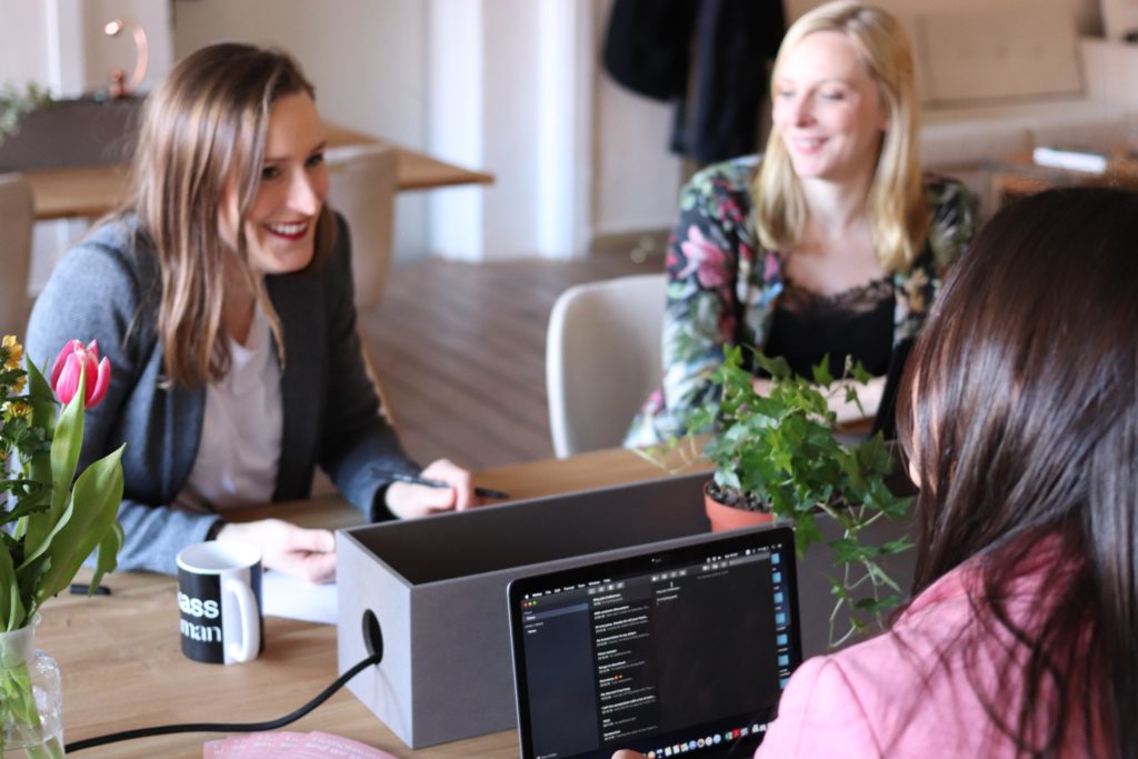 Frauen sitzen mit Computern am Tisch