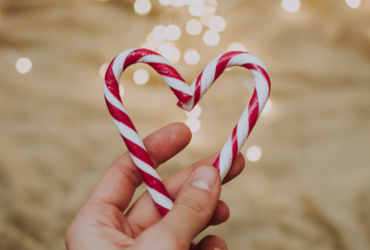 Hand hält Zuckerstangen wie ein Herz