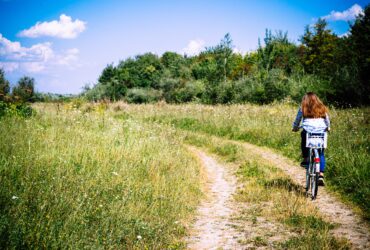 Frau fährt mit dem Fahrrad durch eine Wiese