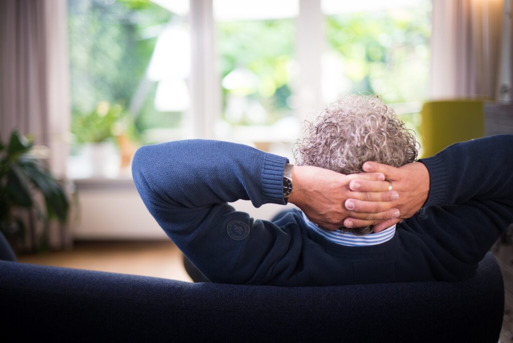 Mann sitzt mit verschränkten Armen auf dem Sofa