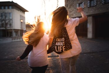 Zwei Mädchen laufen Richtung Sonnenuntergang